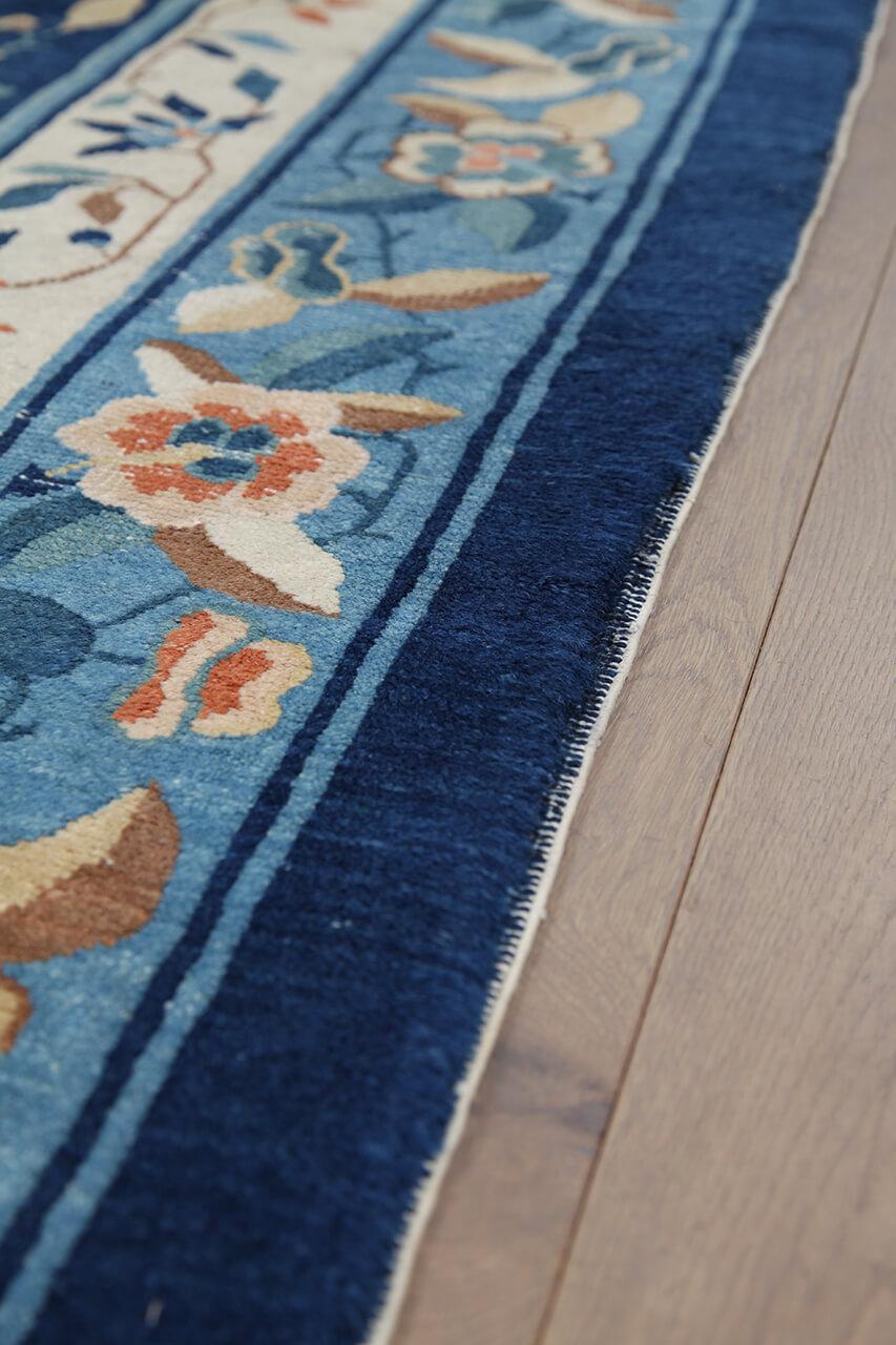 Antikt kinesisk tæppe med blomstermotiver og et dybblåt felt