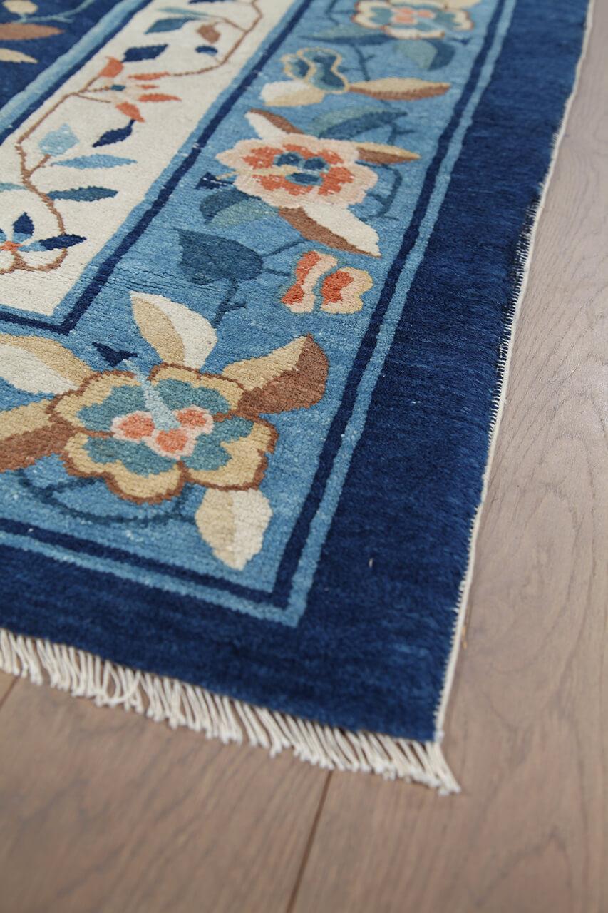 Antikt kinesisk tæppe med blomstermotiver og et dybblåt felt