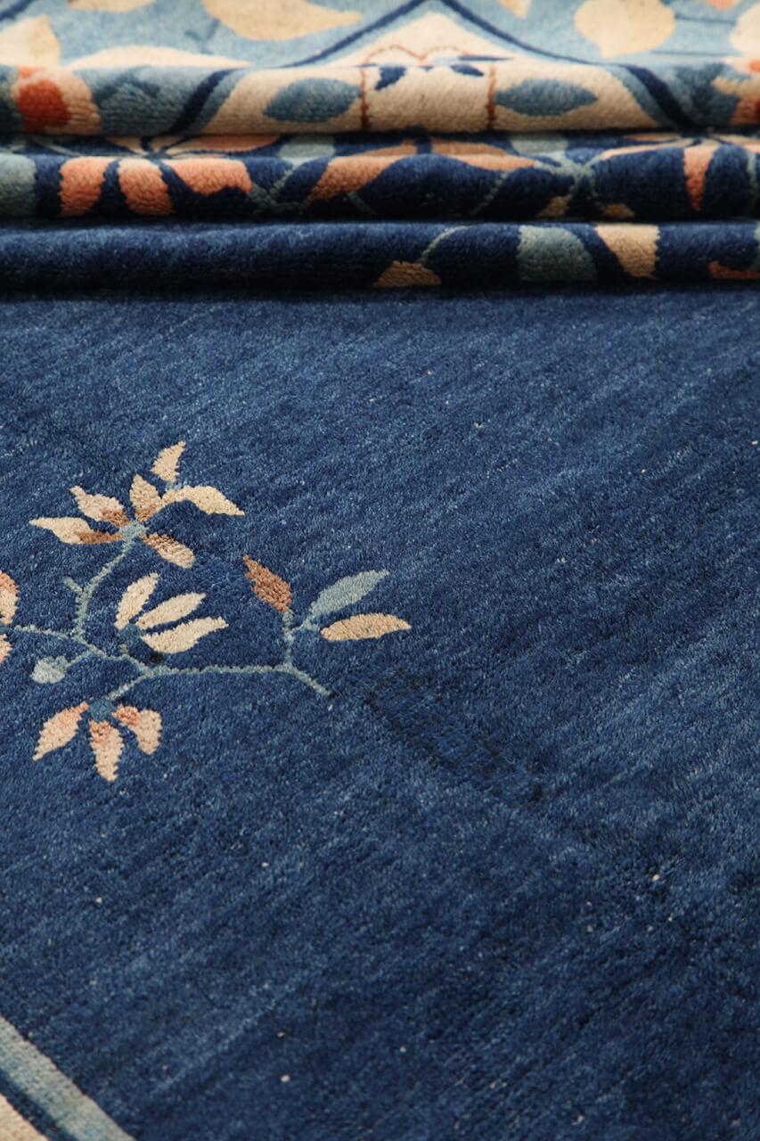 Antikt kinesisk tæppe med blomstermotiver og et dybblåt felt