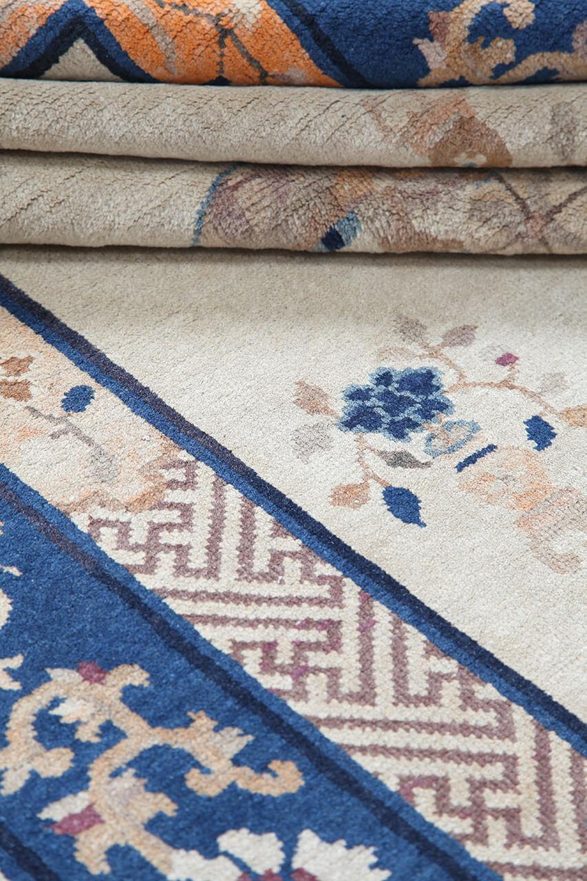 Antikt kinesisk tæppe med traditionelle motiver på en beige bund og blå bort