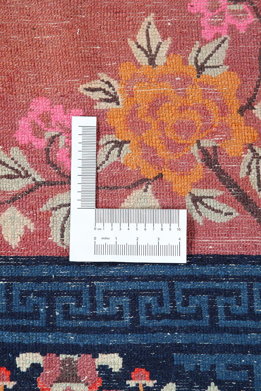 Een prachtig antiek tapijt uit China met een rood veld en bloempatronen.