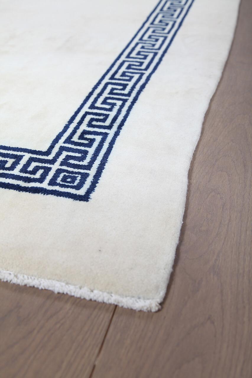 Håndknyttet beige tæppe med en mørk græsk bordkant fra Kina