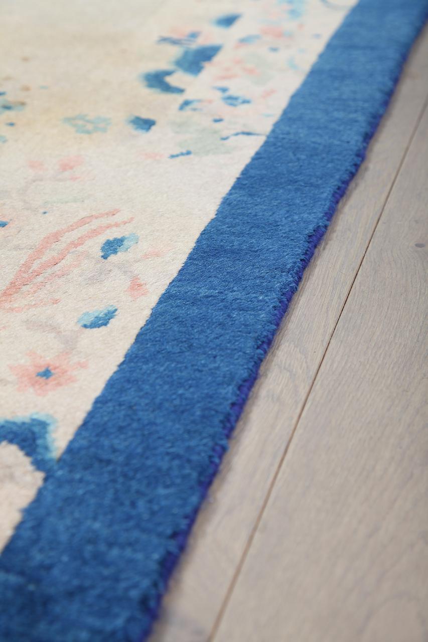 Antikt kinesisk tæppe med central blomstermedaillon og blå kanter i beige og blå toner