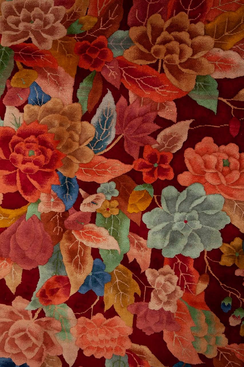 Een handgeknoopt antiek Chinees tapijt met een bloemenboeket op een dieprood veld