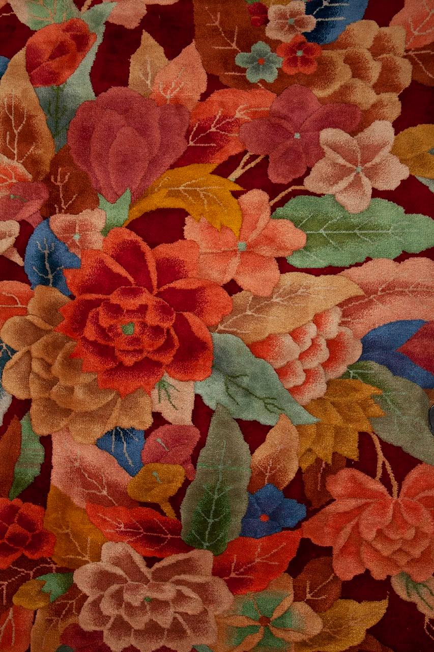 Een handgeknoopt antiek Chinees tapijt met een bloemenboeket op een dieprood veld
