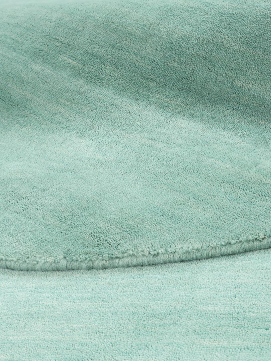 Round teal rug made from wool