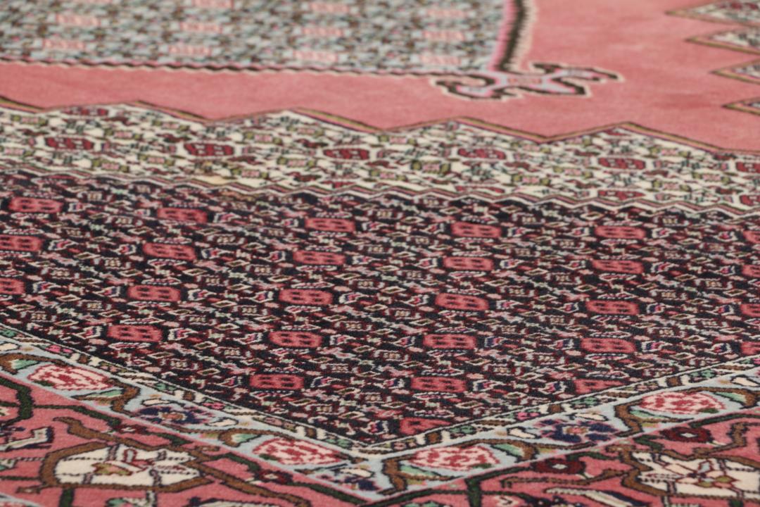 Een uniek handgeknoopt Senneh-tapijt uit het Midden-Oosten in donkerrood en beige.