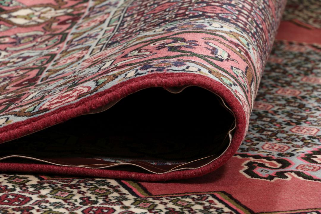 Een uniek handgeknoopt Senneh-tapijt uit het Midden-Oosten in donkerrood en beige.