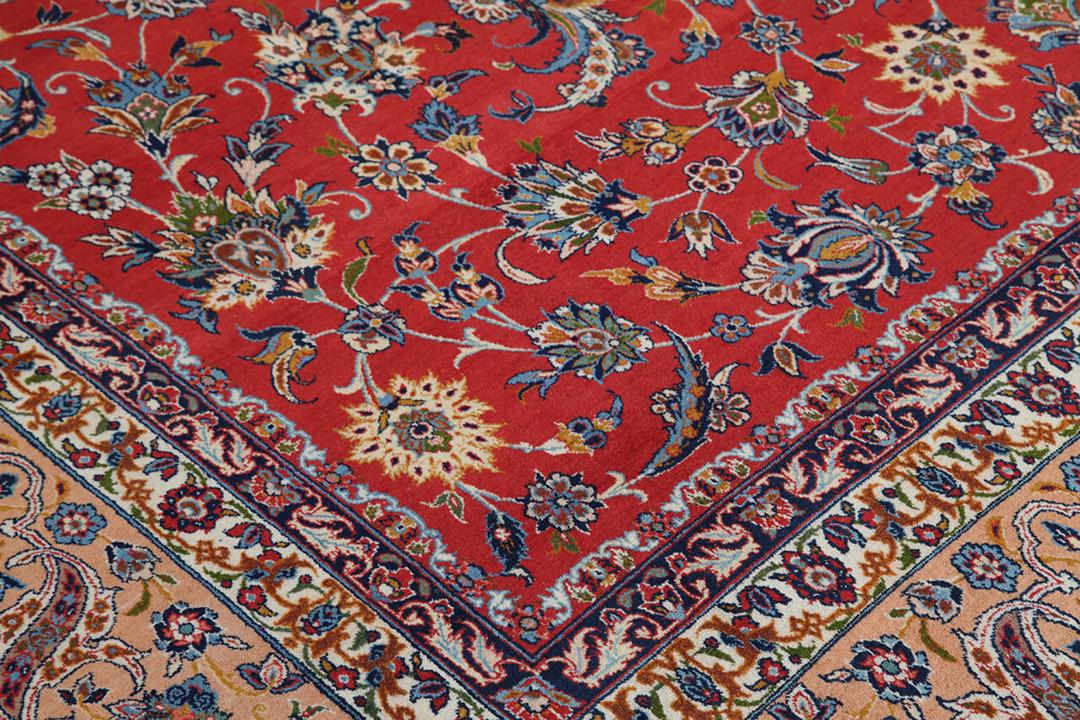 Een groot rechthoekig handgeknoopt Isfahan-tapijt uit het Midden-Oosten in rode en beigetinten.
