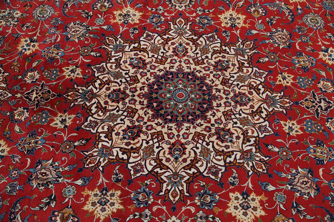 Een groot rechthoekig handgeknoopt Isfahan-tapijt uit het Midden-Oosten in rode en beigetinten.