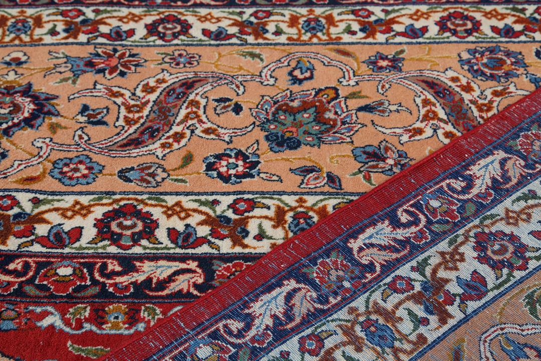 Een groot rechthoekig handgeknoopt Isfahan-tapijt uit het Midden-Oosten in rode en beigetinten.