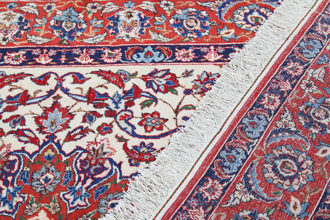 Et smukt antikt Isfahan-tæppe med en indviklet blomstermedaljon i røde og blå nuancer, håndlavet i Mellemøsten.