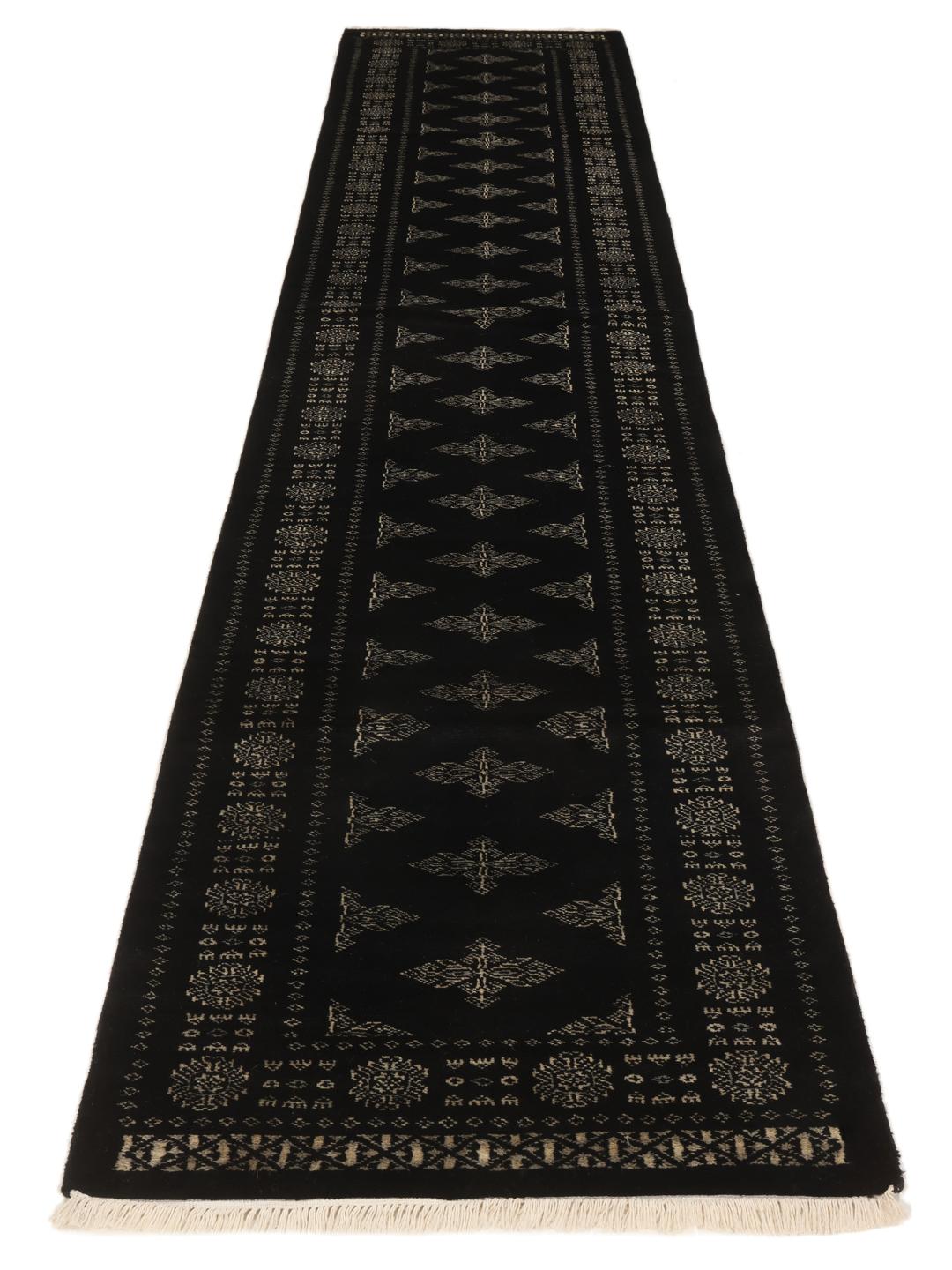 Hand-knotted Pakistan Bokhara runner with intricate motifs on a black background