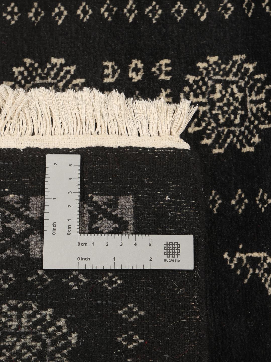 Hand-knotted Pakistan Bokhara runner with intricate motifs on a black background