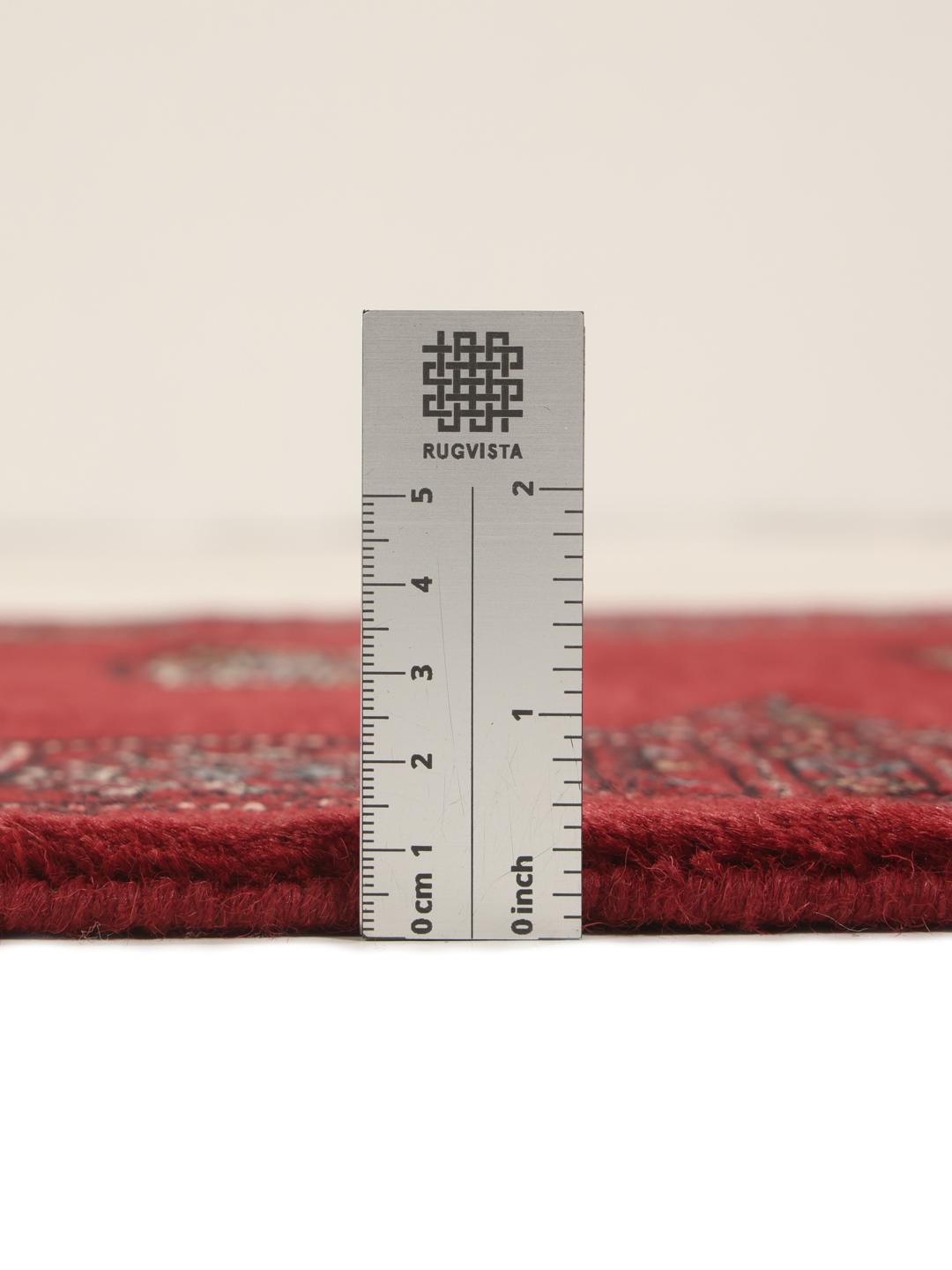 A long, hand-knotted Pakistan Bokhara runner in dark-red with repeating medallion patterns.