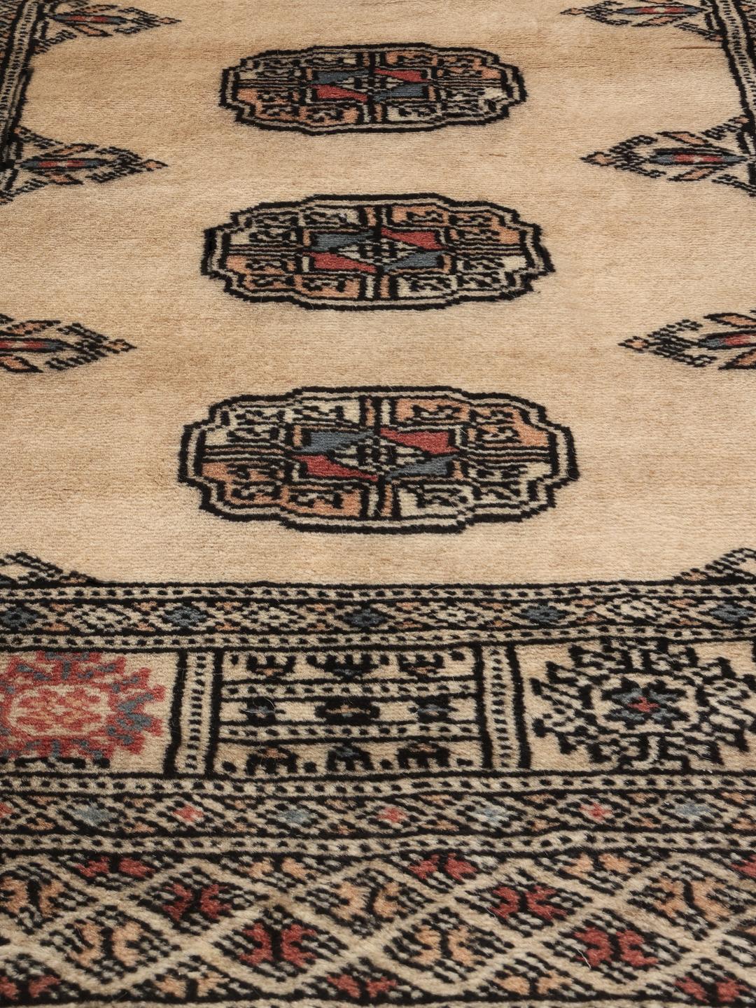 Hand-knotted Pakistan Bokhara runner with beige field and medallion patterns