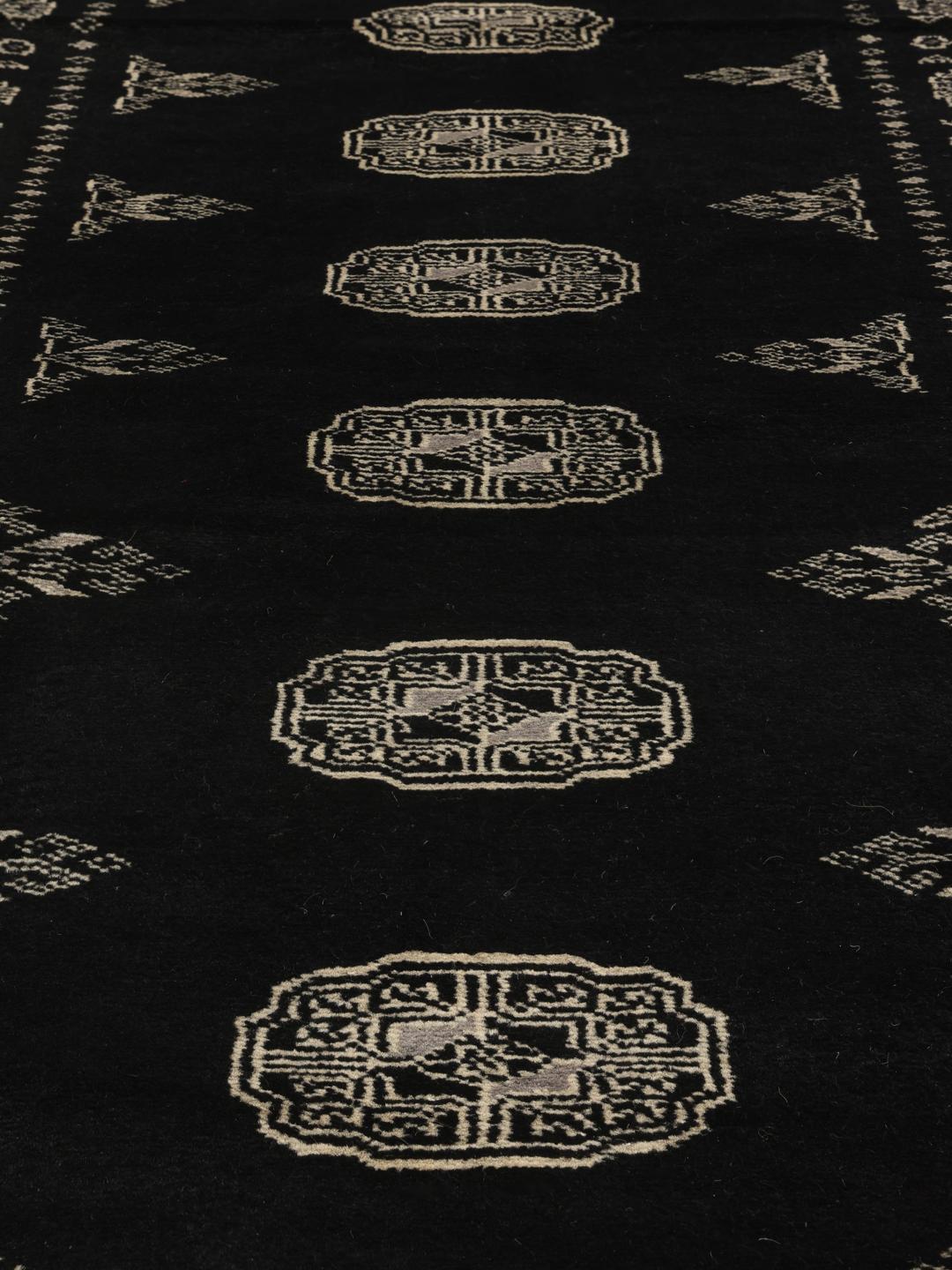 A hand-knotted Pakistan Bokhara runner featuring a black field with geometric motifs