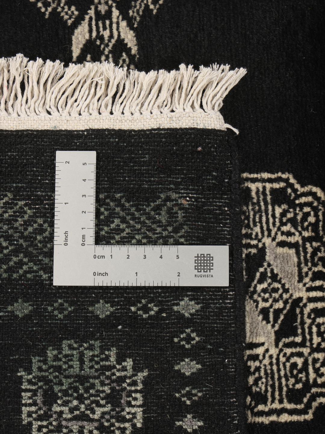 A hand-knotted Pakistan Bokhara runner featuring a black field with geometric motifs