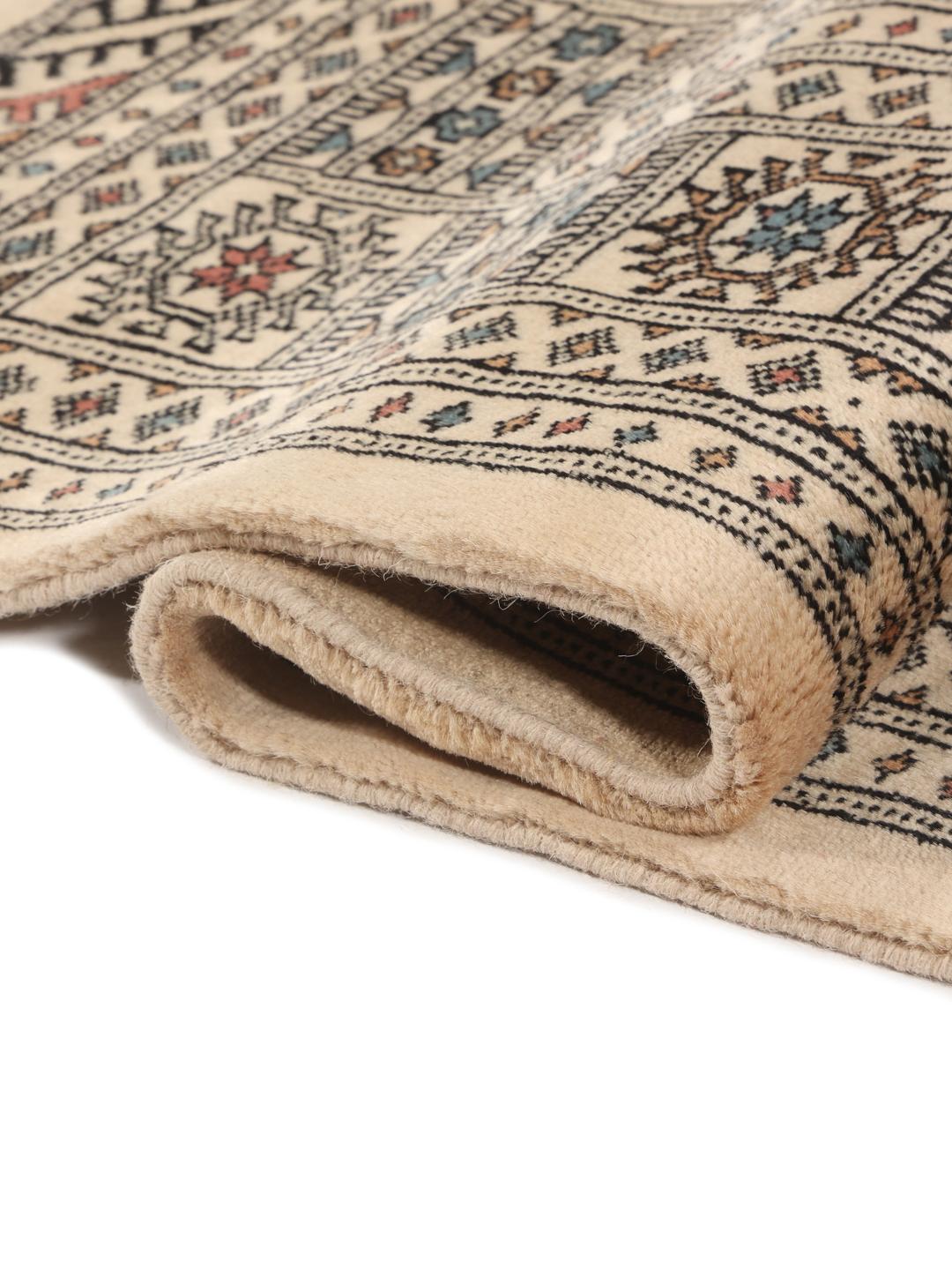 A hand-knotted Pakistan Bokhara rug with a beige field and traditional geometric motifs.
