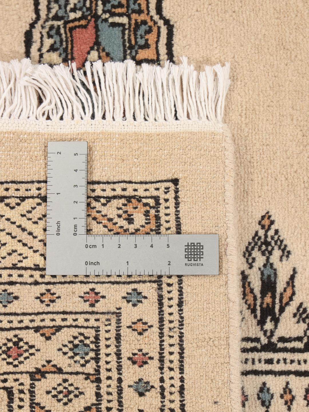 A hand-knotted Pakistan Bokhara rug with a beige field and traditional geometric motifs.