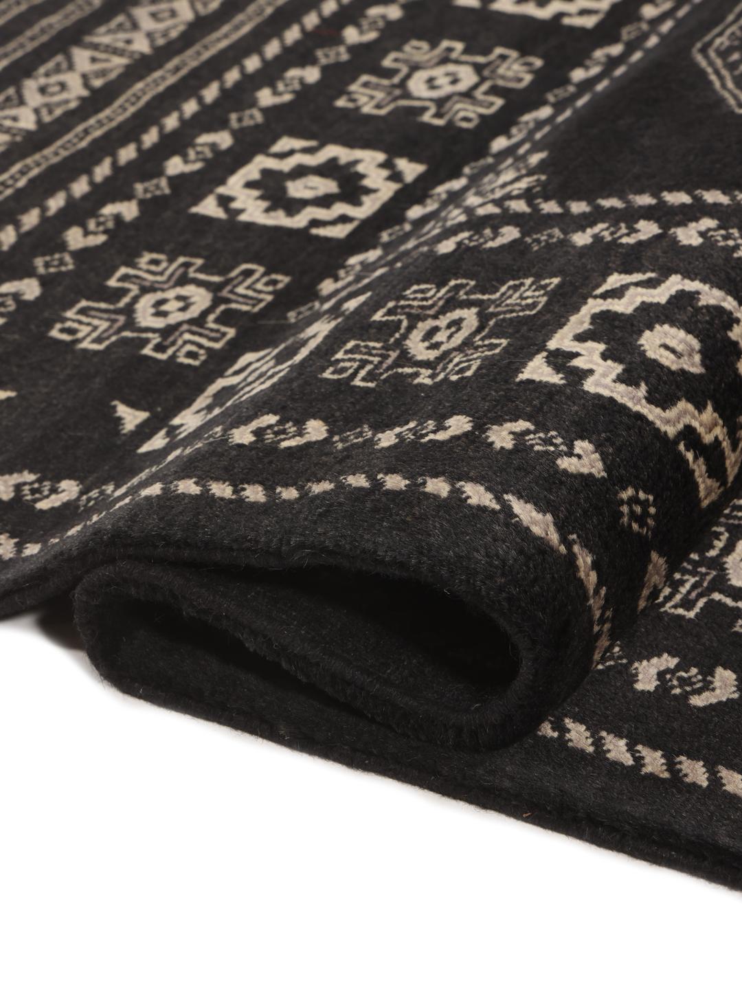 A hand-knotted Pakistan Bokhara rug with a dark field and geometric motifs.