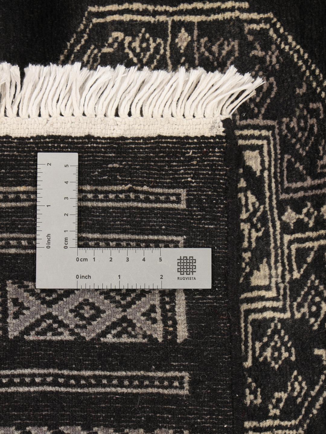 A hand-knotted Pakistan Bokhara rug with a dark field and geometric motifs.