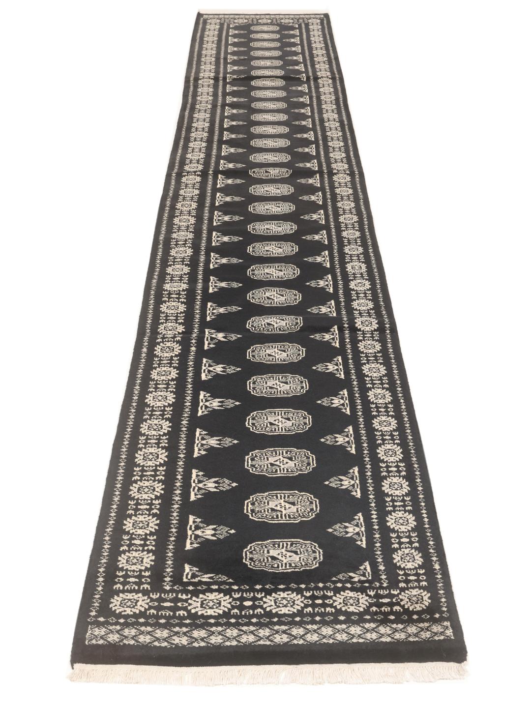 A long, black hand-knotted runner from Pakistan with traditional white motifs.