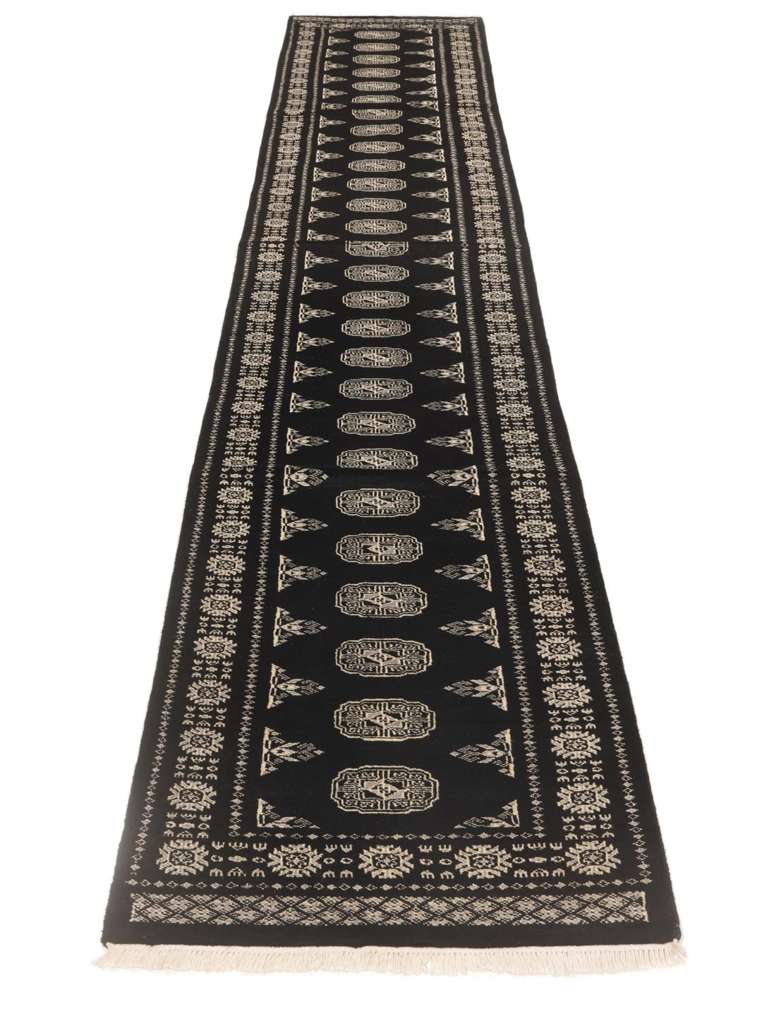 A long, black hand-knotted runner from Pakistan with traditional white motifs.