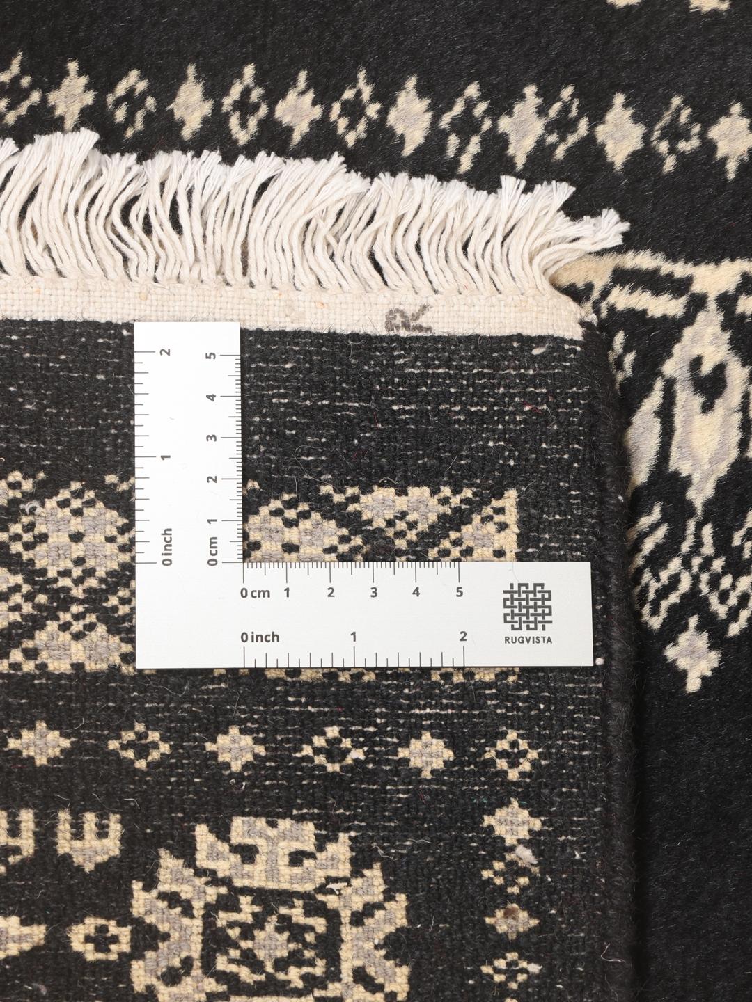 A long, black hand-knotted runner from Pakistan with traditional white motifs.