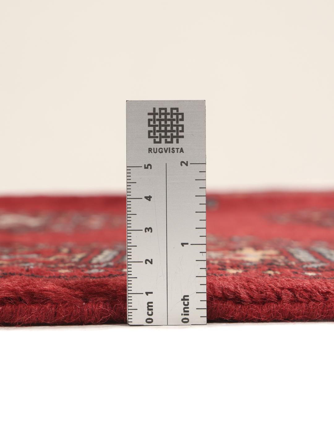 A hand-knotted Pakistan Bokhara rug in deep red with traditional gul motifs.