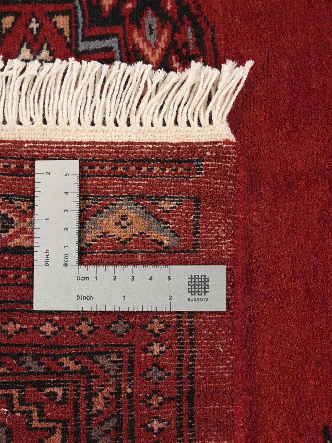 A hand-knotted Pakistan Bokhara rug in deep red with traditional gul motifs.