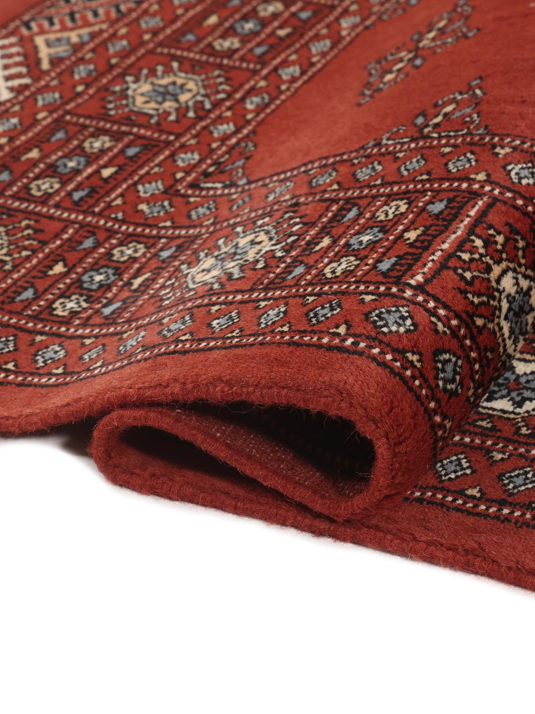 A hand-knotted Pakistan Bokhara rug in deep red with repeating geometric motifs.