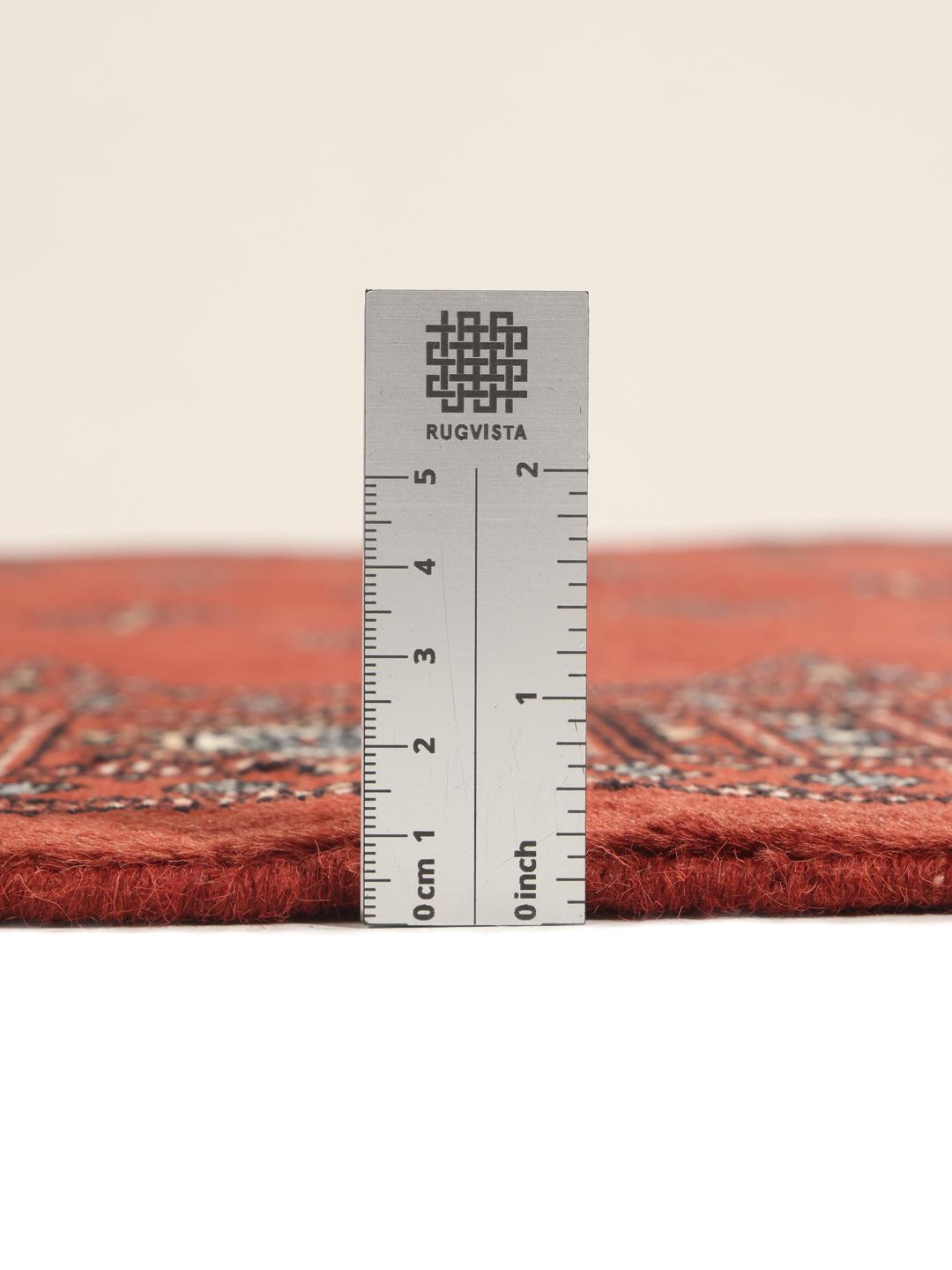 A hand-knotted Pakistan Bokhara rug in deep red with repeating geometric motifs.