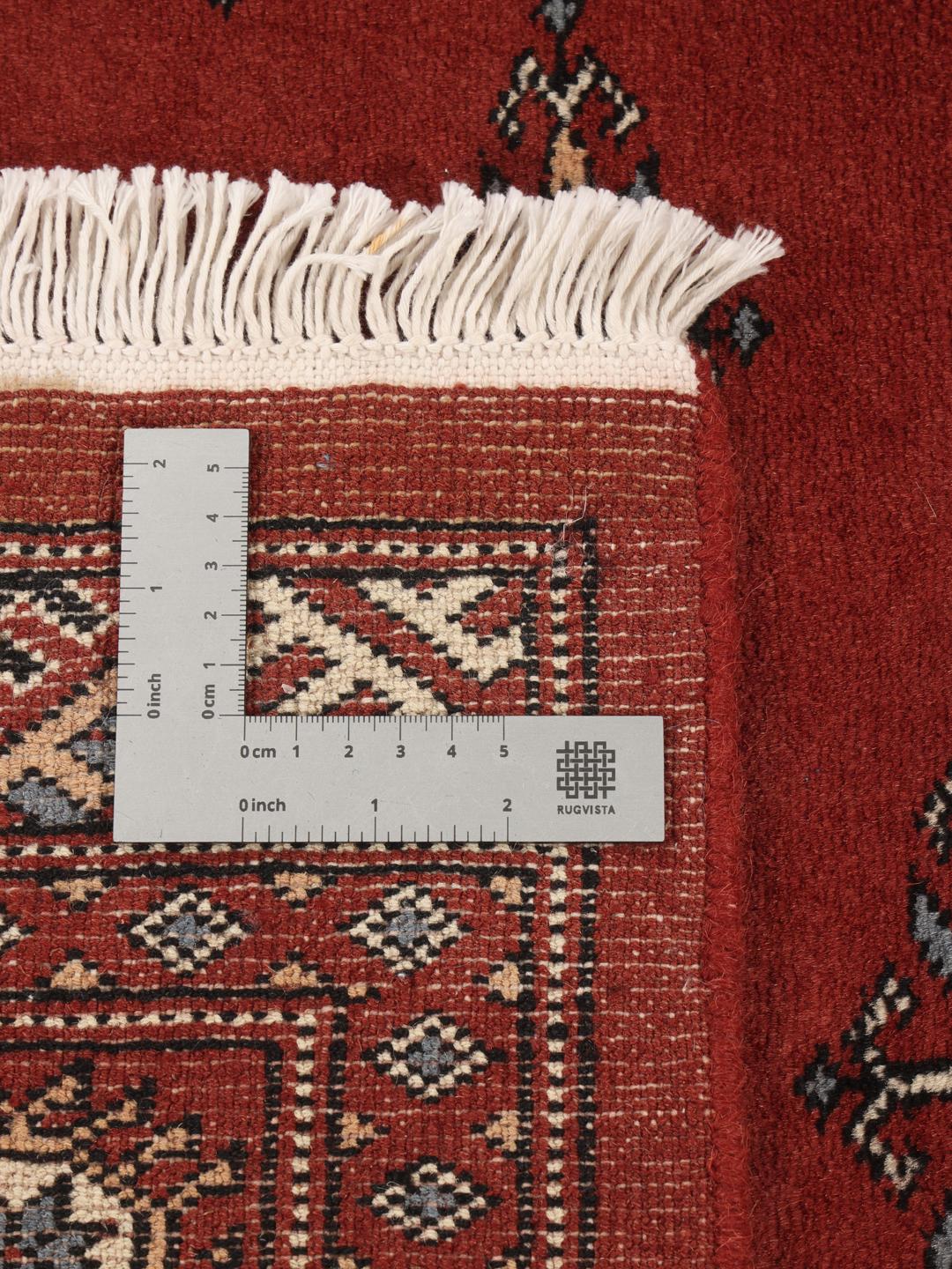 A hand-knotted Pakistan Bokhara rug in deep red with repeating geometric motifs.