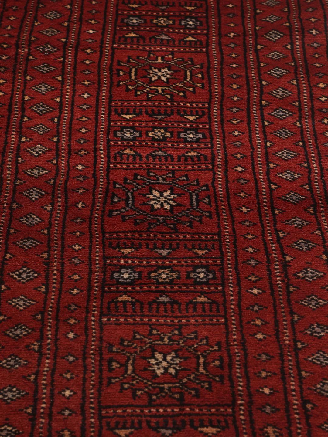 Håndknyttet Pakistan Bokhara 3ply-tæppe i rige røde nuancer med gentagne geometriske motiver.