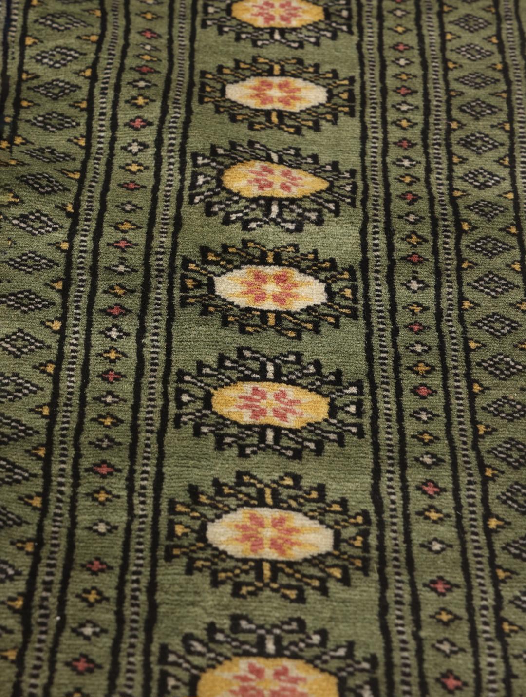 Hand-knotted Pakistan Bokhara rug in green with traditional motifs