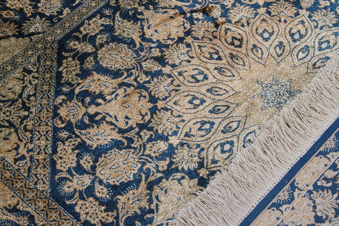 Een luxueus handgeknoopt Qum zijden tapijt uit het Midden-Oosten met blauwe en beige bloemmotieven.