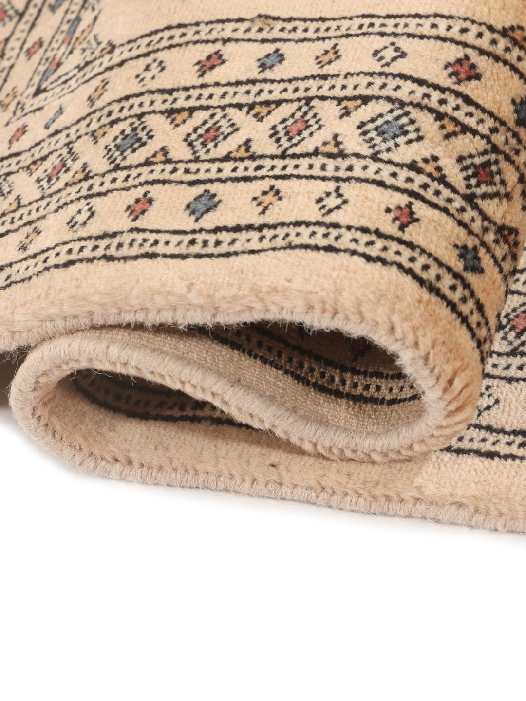 A hand-knotted Pakistani Bokhara rug in beige with traditional medallion motifs.