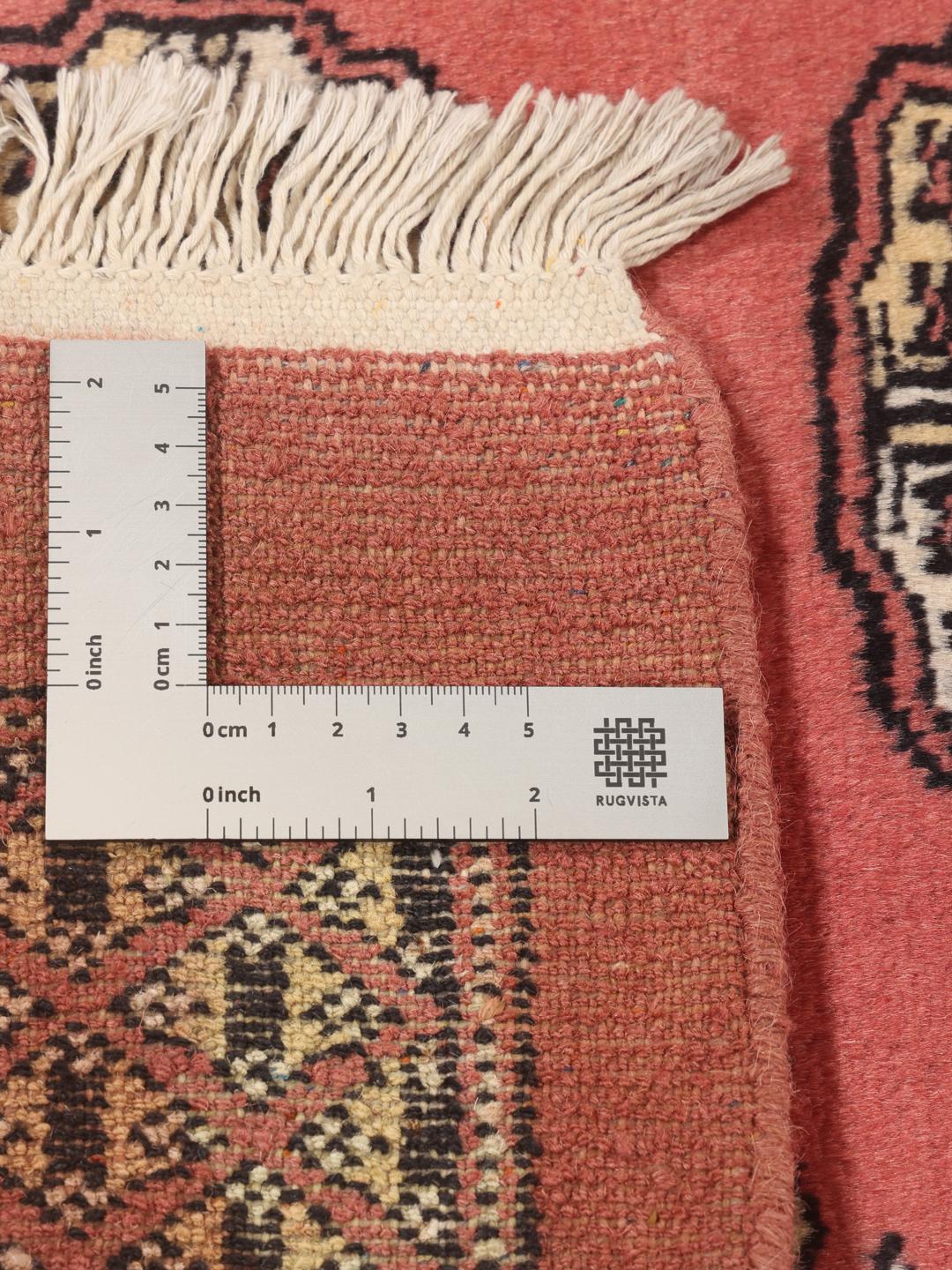 Et håndknyttet rødt Pakistan Bokhara-tæppe med traditionelle geometriske mønstre.
