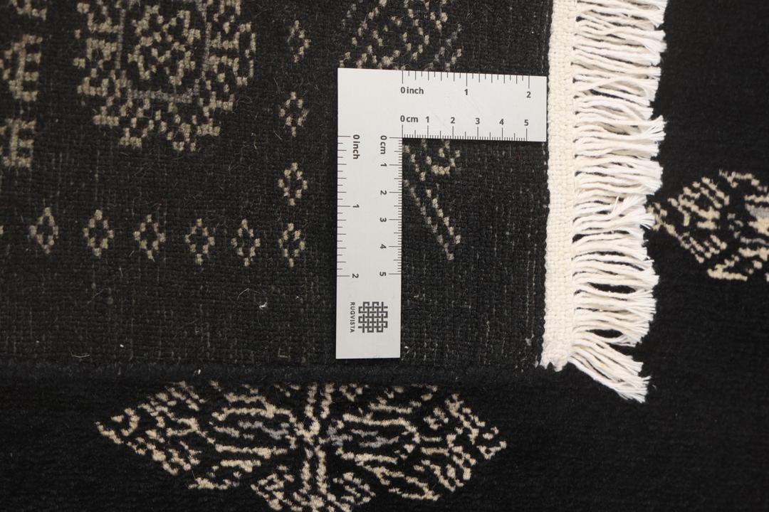 A long, hand-knotted runner from Pakistan with a black field and traditional patterns.