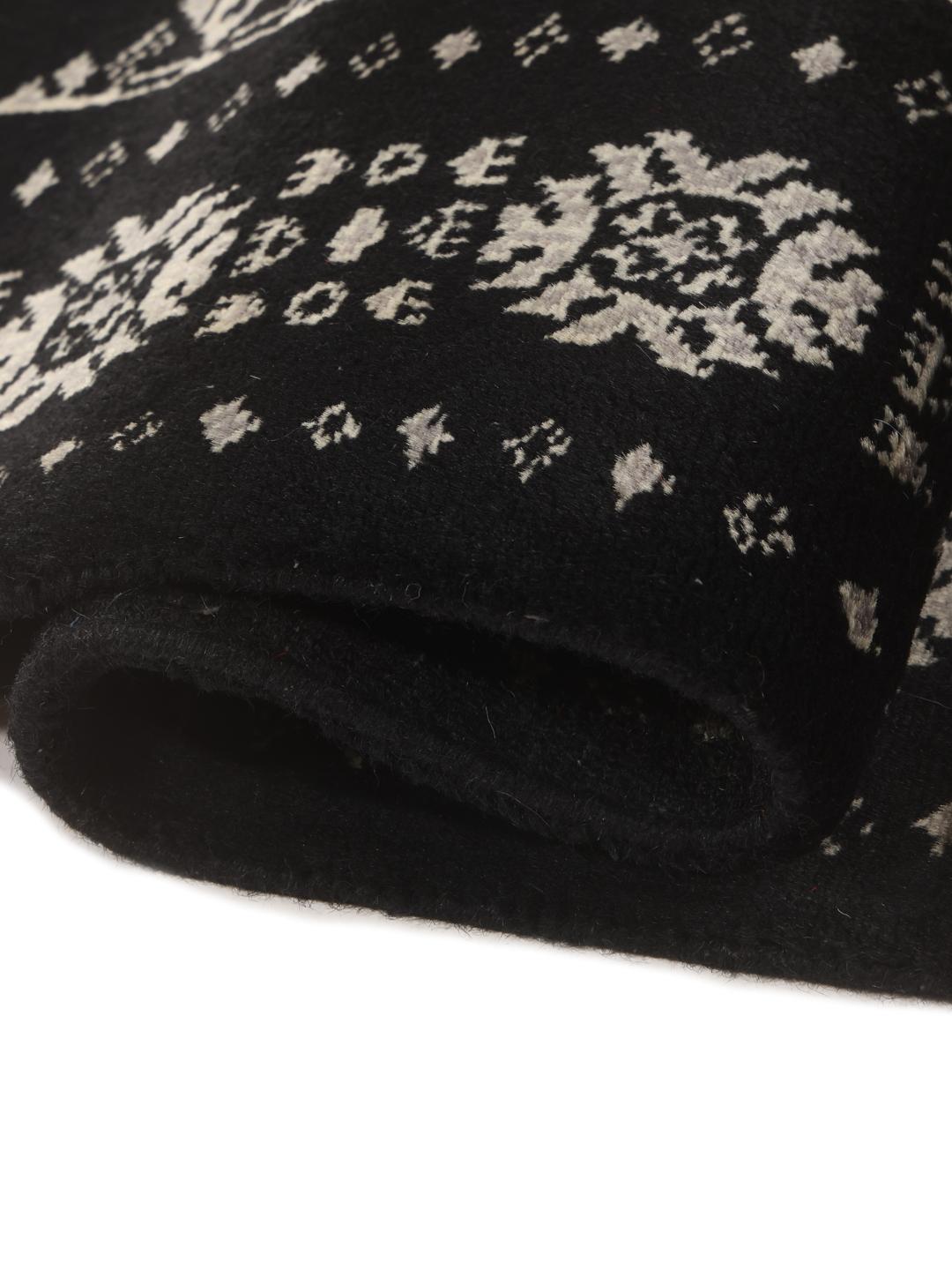 A long, hand-knotted runner from Pakistan with a black field and traditional patterns.