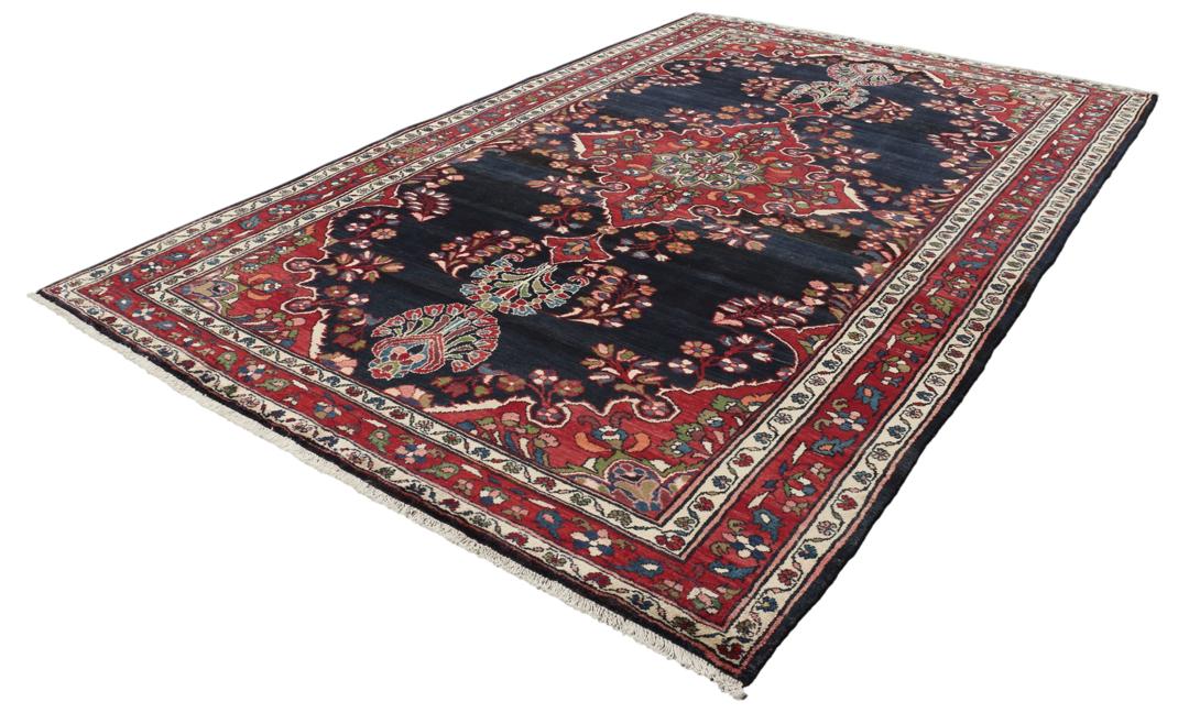 Een handgeknoopt Lillian-tapijt uit het Midden-Oosten met een donkerblauw veld en een centraal rood bloemenmedaillon.