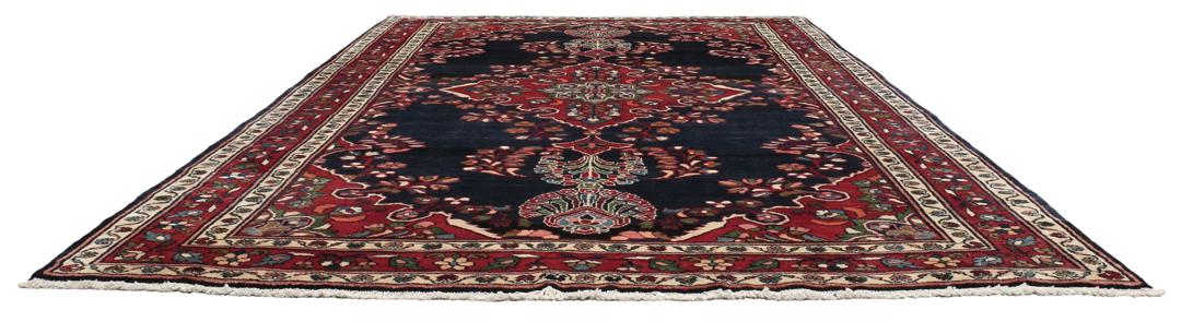 Een handgeknoopt Lillian-tapijt uit het Midden-Oosten met een donkerblauw veld en een centraal rood bloemenmedaillon.
