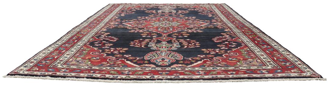 Een handgeknoopt Lillian-tapijt uit het Midden-Oosten met een donkerblauw veld en een centraal rood bloemenmedaillon.