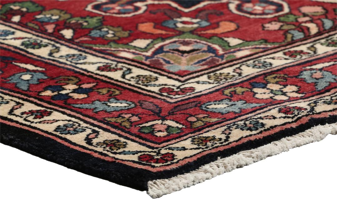 Een handgeknoopt Lillian-tapijt uit het Midden-Oosten met een donkerblauw veld en een centraal rood bloemenmedaillon.