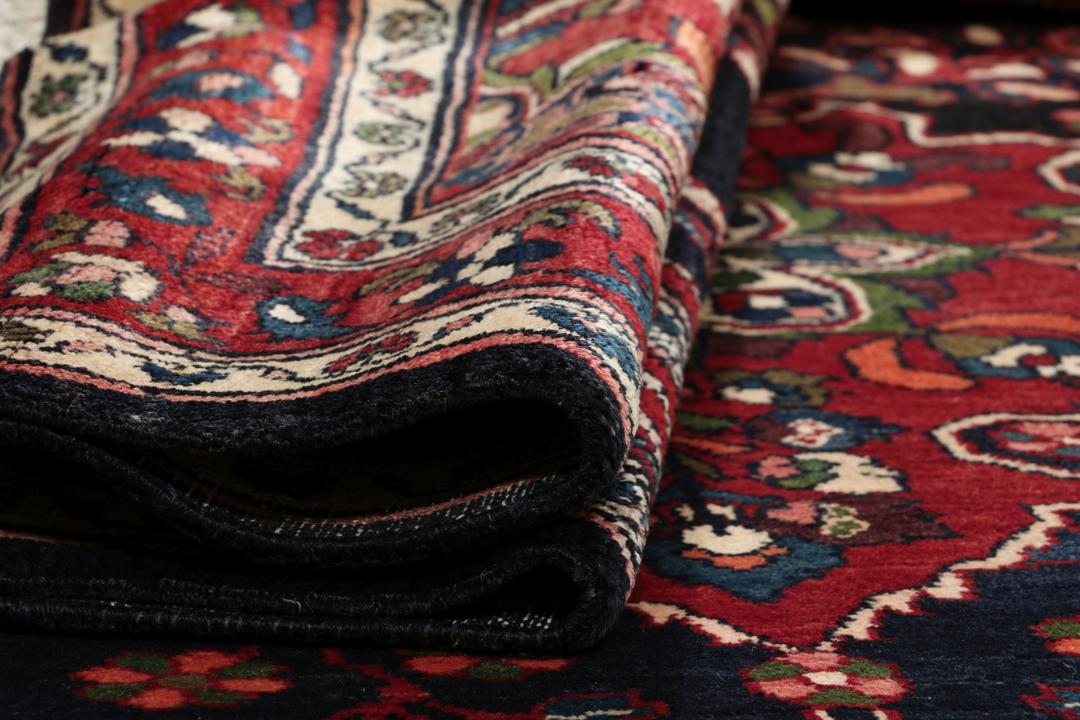 Een handgeknoopt Lillian-tapijt uit het Midden-Oosten met een donkerblauw veld en een centraal rood bloemenmedaillon.