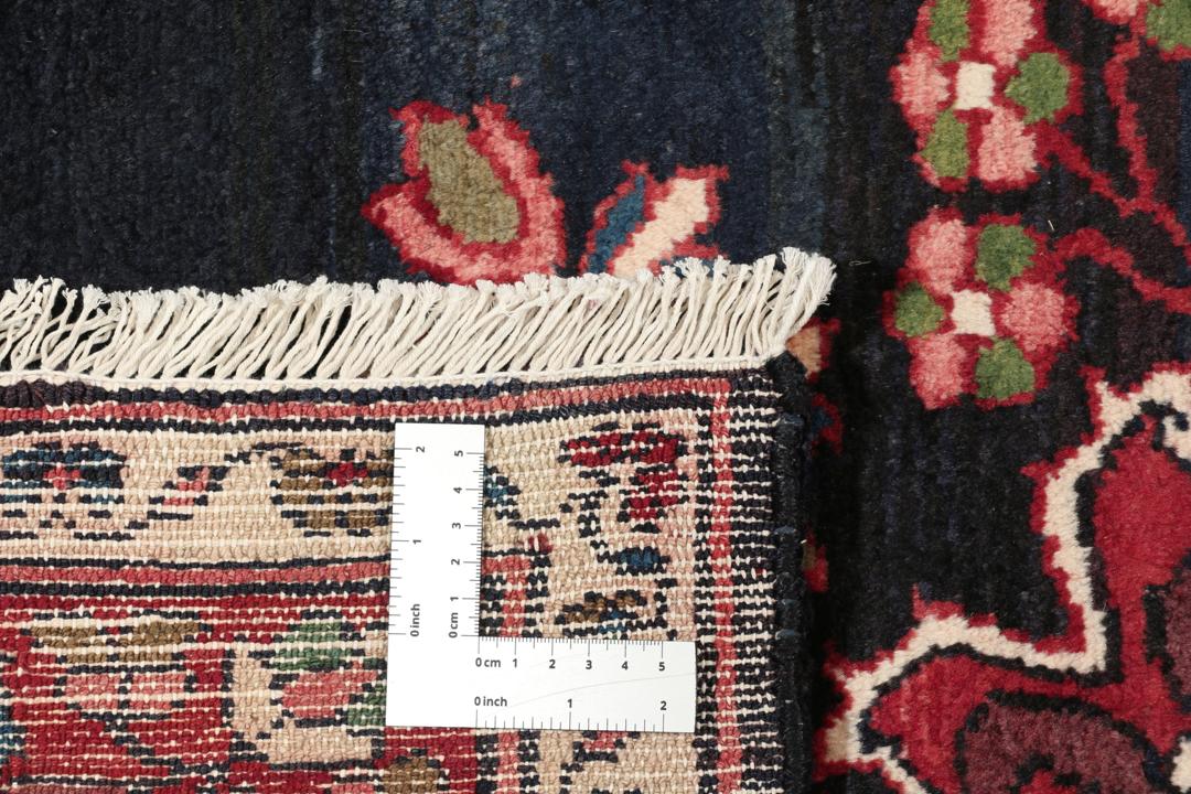 Een handgeknoopt Lillian-tapijt uit het Midden-Oosten met een donkerblauw veld en een centraal rood bloemenmedaillon.