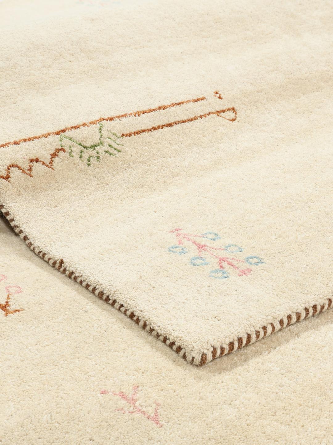 Et beige tæppe med små, spredte dekorative motiver.