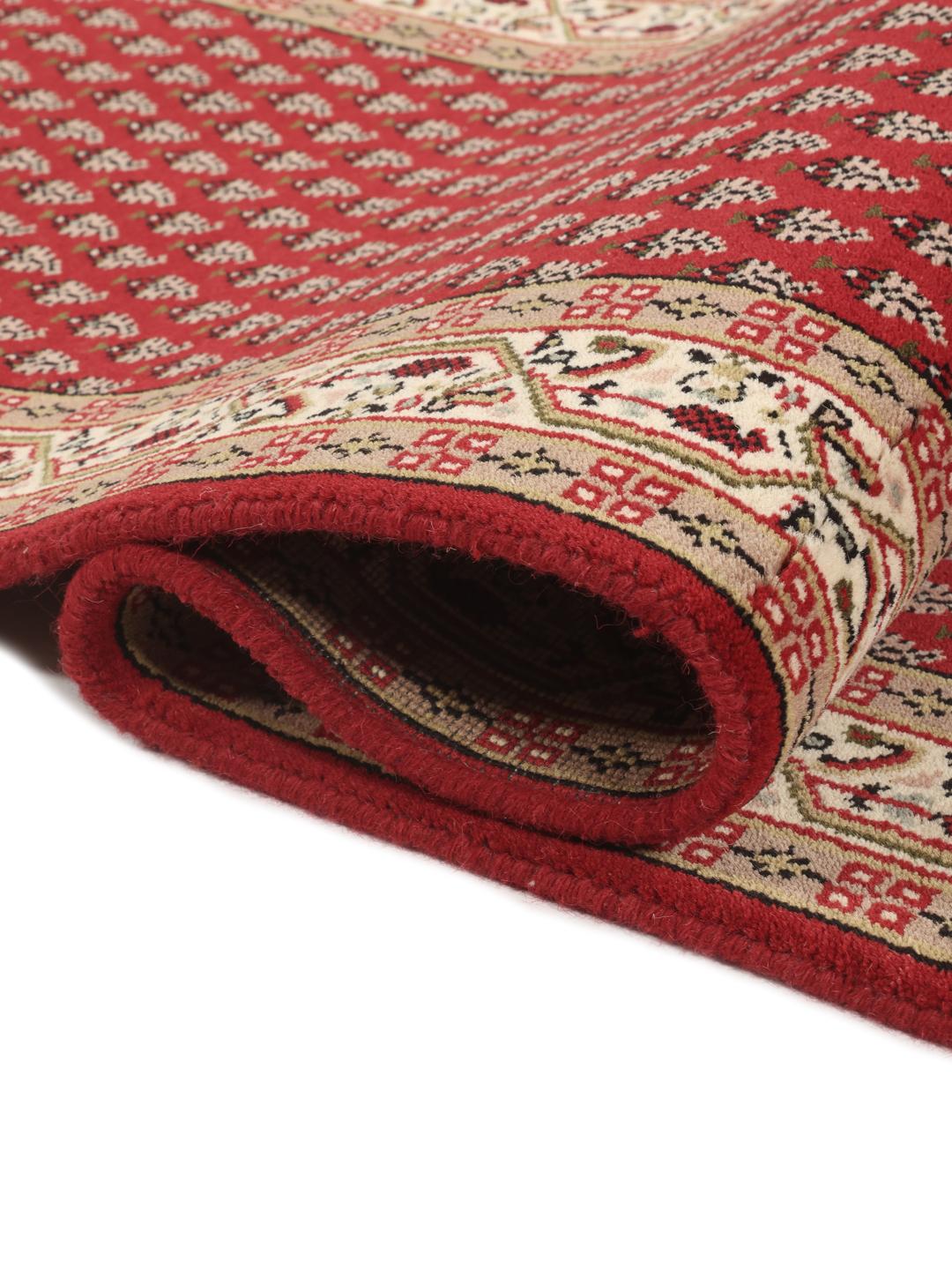 Un long tapis de couloir Mir Indo noué à la main, originaire d'Inde, avec un champ rouge profond et un motif floral complexe.
