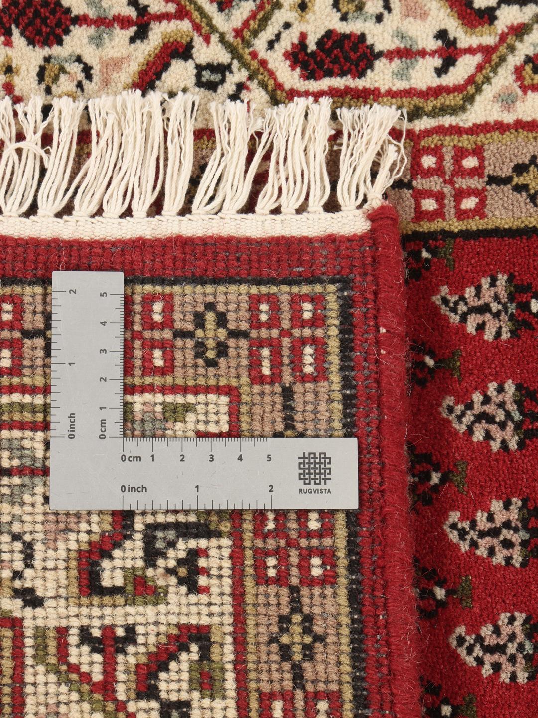 Un long tapis de couloir Mir Indo noué à la main, originaire d'Inde, avec un champ rouge profond et un motif floral complexe.